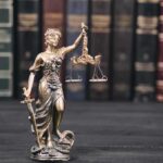 Life-Insurance Kill? Clemency Shot Down Lady Justice statue with scales in front of law books