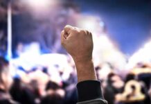 Raised fist at a nighttime crowd