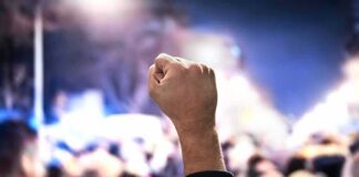 Raised fist at a nighttime crowd