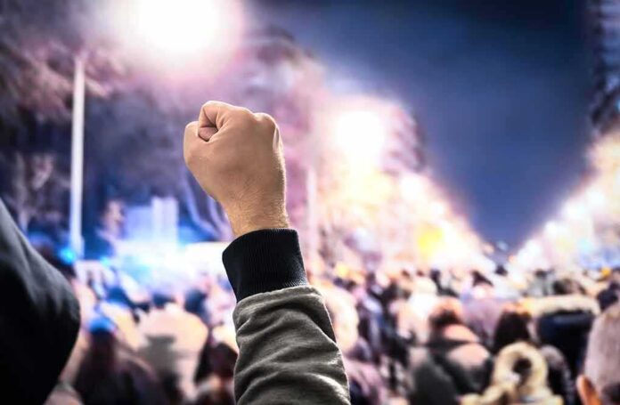 Raised fist in front of a large crowd at night
