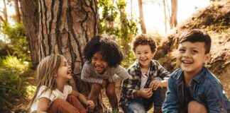 Group of children laughing together in a sunny forest