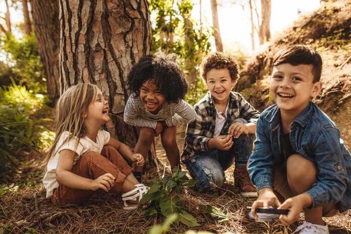 Group of children laughing together in a sunny forest