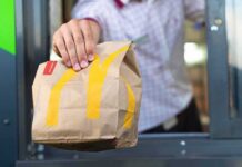Drive-thru worker handing a branded paper bag