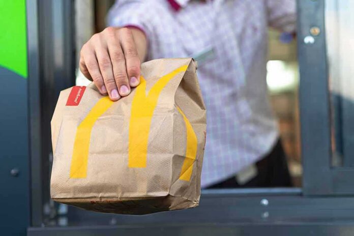Drive-thru worker handing a branded paper bag