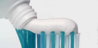 Toothbrush with toothpaste being squeezed onto bristles