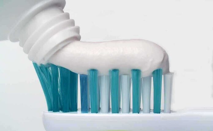 shutterstock_1638835894 Toothbrush with toothpaste being squeezed onto bristles