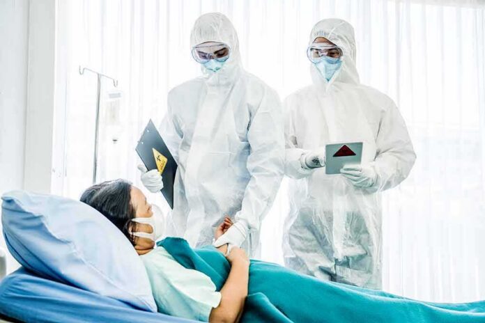 shutterstock_1646389288 Medical staff in hazmat suits attend to a patient in a hospital bed