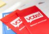 Red vote return envelopes on a table