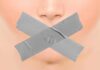 Close-up face with mouth covered by crossed duct tape