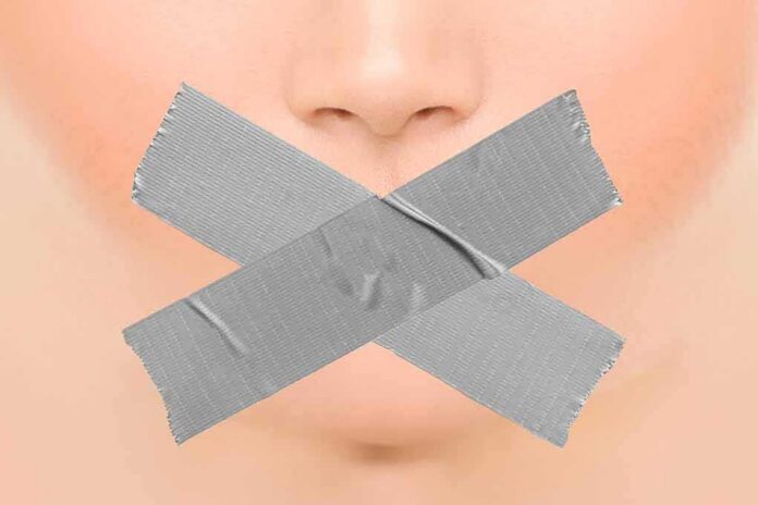 Close-up face with mouth covered by crossed duct tape