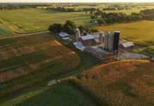 Trump’s Farm Cash: Phantom Billions Inflate Aid Aerial view of a farm with silos and barns amid golden crop fields