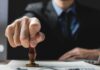 Mass Denaturalization Wave Shocks Courts – Targets Hidden Crimes Hand stamping a document on a desk