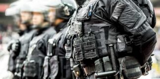 Riot police officers in tactical gear standing in a line